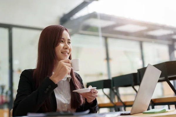 stock image Portrait of Asian economist, accountant, marketer drinking coffee and using computer in office.