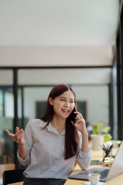 Asyalı iş kadını iş ortağıyla görüşmek için telefonu kullanıyor..