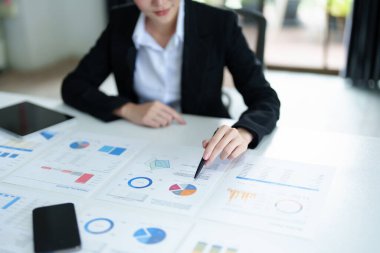 Düşünceli bir Asyalı iş kadınının portresi. Masasındaki tablet bilgisayarla finansal tabletlere bakıyor ve pazarlama planları yapıyor..