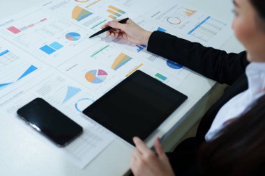 Düşünceli bir Asyalı iş kadınının portresi. Masasındaki tablet bilgisayarla finansal tabletlere bakıyor ve pazarlama planları yapıyor..