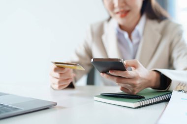 İnternetten alışveriş için kredi kartı ve telefon kullanan Asyalı genç bir kadının portresi..