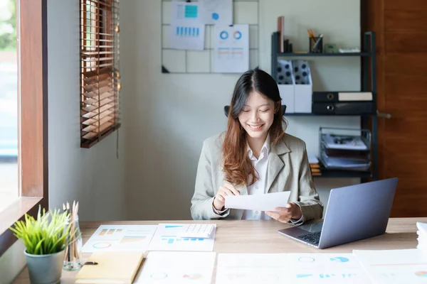 財務諸表を見る思慮深いアジアの実業家の肖像画と彼女の机の上にコンピュータを使用してマーケティング計画を立てる — ストック写真