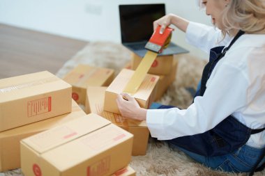 Çevrimiçi pazarlama paketi ve KOBİ teslimat kavramının neşeli başarısı ile bilgisayar laptopu kullanarak gülümseyen bağımsız Asyalı kadının küçük işletme girişimciliğini başlatan.