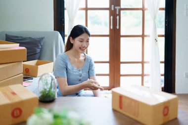 Çevrimiçi pazarlama paketi ve KOBİ teslimat kavramının neşeli başarısı ile bilgisayar laptopu kullanarak gülümseyen bağımsız Asyalı kadının küçük işletme girişimciliğini başlatan.