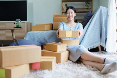 Çevrimiçi pazarlama paketi ve KOBİ teslimat kavramının neşeli başarısı ile bilgisayar laptopu kullanarak gülümseyen bağımsız Asyalı kadının küçük işletme girişimciliğini başlatan.