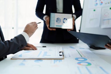 Toplantı odasındaki mali raporda durumu analiz etmek ve tartışmak için takım iş danışmanı toplantısı. Tablet, hesap makinesi, doküman ve bilgisayar kullanılıyor.