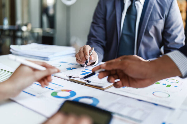 Team business adviser meeting to analyze and discuss the situation on the financial report n the meeting room with using documents, calculator, computer laptop in work