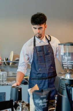 Asyalı erkek barista müşteriler için kahve yapıyor..