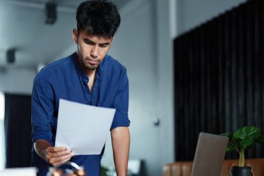 Masasında oturan yakışıklı ve ağzı sıkı Asyalı bir adamın portresi. Bilgisayarında düşünceli bir bakış var..