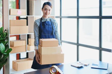 Bağımsız Asyalı kadın çevrimiçi satıcının müşterilere ve KOBİ dağıtım konseptine göndermek üzere ürünlerini paketleyen küçük işletme girişimcisi başlatılıyor.