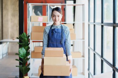 Bağımsız Asyalı kadın çevrimiçi satıcının müşterilere ve KOBİ dağıtım konseptine göndermek üzere ürünlerini paketleyen küçük işletme girişimcisi başlatılıyor.