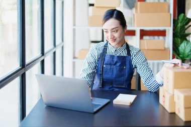 Bağımsız Asyalı kadın çevrimiçi satıcının müşterilere ve KOBİ dağıtım konseptine göndermek üzere ürünlerini paketleyen küçük işletme girişimcisi başlatılıyor.