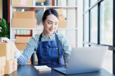 Bağımsız Asyalı kadın çevrimiçi satıcının müşterilere ve KOBİ dağıtım konseptine göndermek üzere ürünlerini paketleyen küçük işletme girişimcisi başlatılıyor.