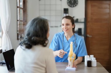 Yaşlı bir hastayla kemik iltihabı hakkında konuşan bir kadın doktorun portresi.