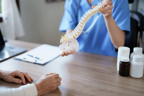 一位女医生与一位老年病人谈论因长时间工作而导致椎间盘突出恶化的画像 — 图库照片