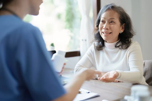 Yaşlı bir hastaya ilaç veren bir kadın doktorun portresi.