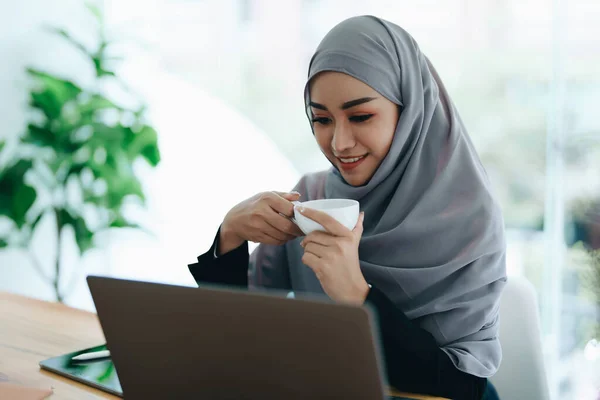 Красивая Мусульманка Улыбающимся Лицом Утрам Пьет Кофе Пользуется Компьютером — стоковое фото