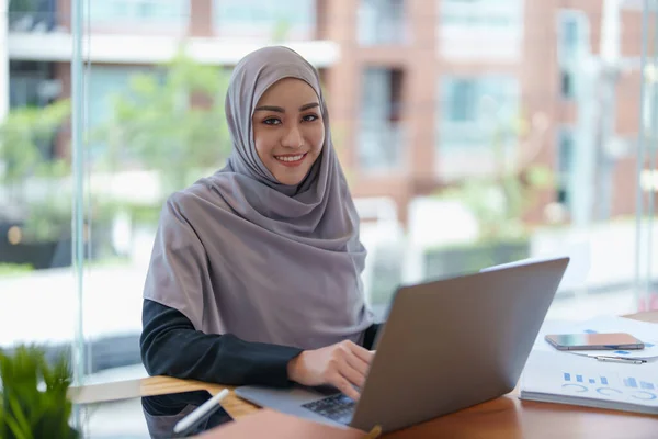 stock image A beautiful Muslim woman showing a smiling face in the morning using computers and documents working at the office.