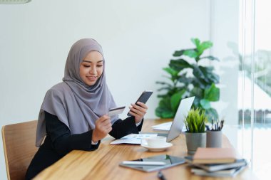 Güzel Müslüman kadın internetten telefon ve kredi kartıyla alışveriş yapıyor..
