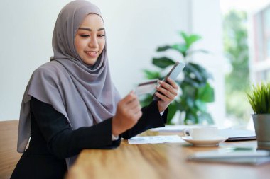 Güzel Müslüman kadın internetten telefon ve kredi kartıyla alışveriş yapıyor..