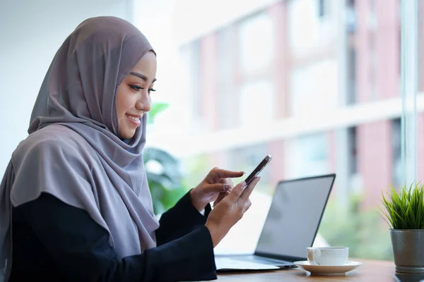 stock image Beautiful Muslim woman talking on the phone and using a computer on her desk.