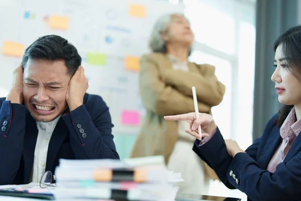 stock image An image of an Asian male employee looking worried and sad about being scolded by his boss for failing to meet sales targets, concept of disappointment and failure in his career.