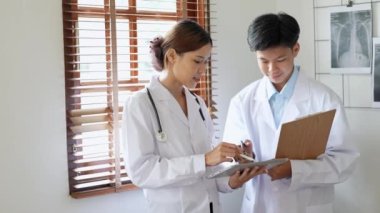 Genç Asyalı kadın doktor, işe gitmek için tablet kullanan bir hastayı ameliyata hazırlamak için danışmanla konuşuyor. Yüksek kalite 4k görüntü