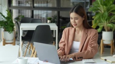 Bilgisayarı, hesap makinesini ve önemli belgeleri kullanarak bütçe ve pazarlama planı üzerinde çalışan Asyalı genç bir iş kadını ya da muhasebeci. Yüksek kalite 4k görüntü