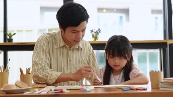 アジア系の可愛い女の子が筆を使って男性教師と絵を描く活動をしています 高品質4K映像 — ストック動画