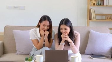 İki güzel Asyalı kız heyecanlı ifadeli bilgisayar kullanıyor. Yüksek kalite 4k görüntü