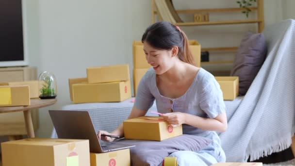 独立した若いアジアの女性オンライン販売業者の小企業起業家を開始するコンピュータを使用しており 顧客への配信のための製品をパックするために注文を取っている 中小企業の配送コンセプト 高品質 — ストック動画