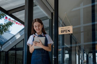 Başlangıçta başarılı olan küçük işletme sahibi, elinde tabletle kafede duran, Asyalı esmer kadın kafe sahibi, girişimci iş adamı konsepti..