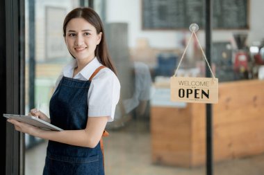 Başlangıçta başarılı olan küçük işletme sahibi, elinde tabletle kafede duran, Asyalı esmer kadın kafe sahibi, girişimci iş adamı konsepti..