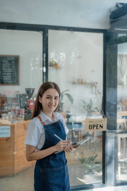 Başlangıçta başarılı olan küçük işletme sahibi, elinde tabletle kafede duran, Asyalı esmer kadın kafe sahibi, girişimci iş adamı konsepti..