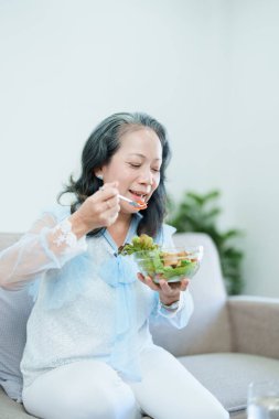 Yaşlı bir Asyalı kadının portresi salata yiyerek sağlığına dikkat ediyor.