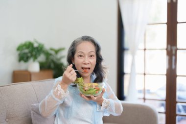 Yaşlı bir Asyalı kadının portresi salata yiyerek sağlığına dikkat ediyor.