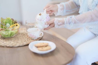 Sebze salatası ve atıştırmalık yerken sağlıklı çay içen yaşlı bir Asyalı kadının portresi.