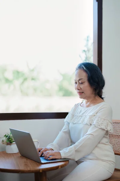 Portrait of an elderly Asian woman in a modern pose working on a computer