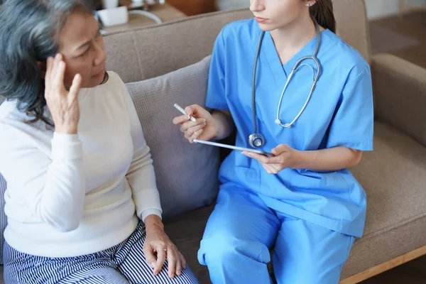 stock image Portrait of a female doctor holding a tablet taking a note of a patients symptoms to discuss and analyze a headache