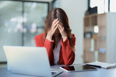 Masasındaki telefon ve mali belgeleri kullanırken stresli yüzünü gösteren güzel bir Asyalı kadın çalışanın portresi..