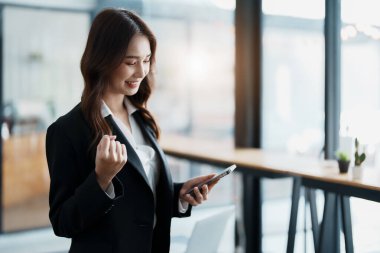 İş konsepti, cep telefonu tutan genç bir iş kadınının portresi mutlu bir yüz ifadesi, iş başarısı