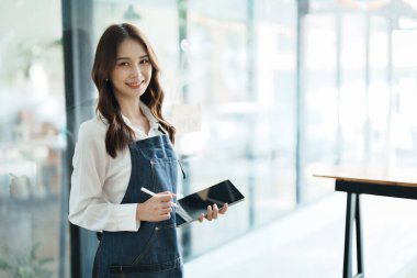 Kafenin önünde elinde tabletle mutlu bir Asyalı kadının portresini aç.