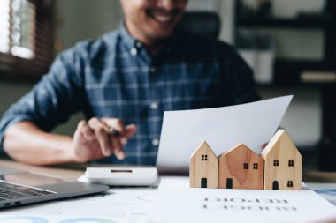 Entrepreneurs, business owners, accountants, real estate agents, A young man using a calculator to calculate his home budget to assess the risks of investing in real estate.