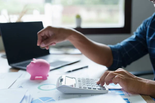 stock image Portrait of an Asian businessman using a calculator to calculate his savings from SME operations, with a pink piggy bank as keep money concept.