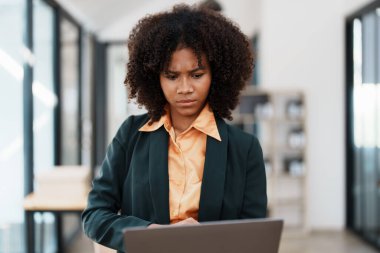 Genç ve güzel Afrikalı bir iş kadını dizüstü bilgisayara bakarken düşünceli, rapor ya da e-posta okurken stresli. Çevrimiçi pazarlama sorunu, finansal hata, sorun yaratma.