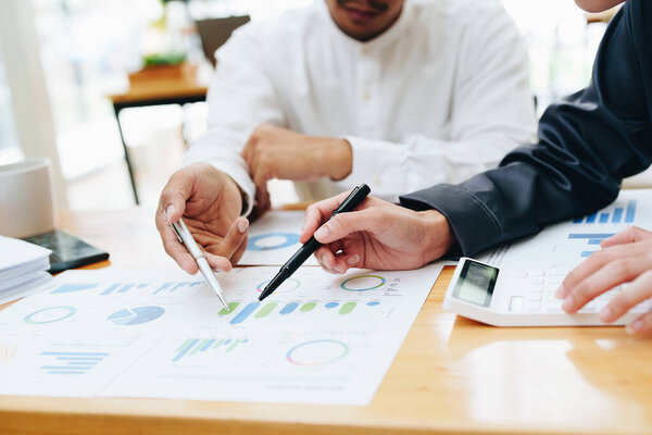 Портрет двух предпринимателей, использующих компьютеры, калькуляторы и финансовые бюджетные документы для планирования маркетинговых усилий по увеличению прибыли.