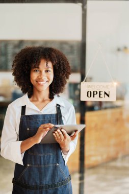 Başlangıçta başarılı, küçük, güzel, Afrikalı, güzel bir kız kahve dükkanında tabletle duruyor. Girişimci iş konsepti..