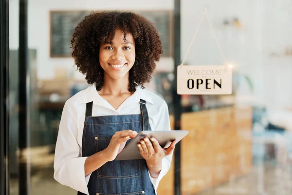 Başlangıçta başarılı, küçük, güzel, Afrikalı, güzel bir kız kahve dükkanında tabletle duruyor. Girişimci iş konsepti..