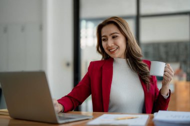 Bilgisayarda konuşan ve kahve içen bir iş kadını portresi..