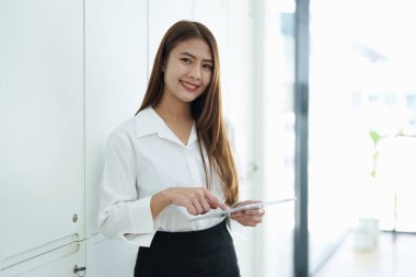 İşyerinde bilgisayarları ve finansal bütçe belgelerini kullanarak başarılı bir şekilde yatırım yaptığı için gülümseyen bir kadın işadamının portresi..